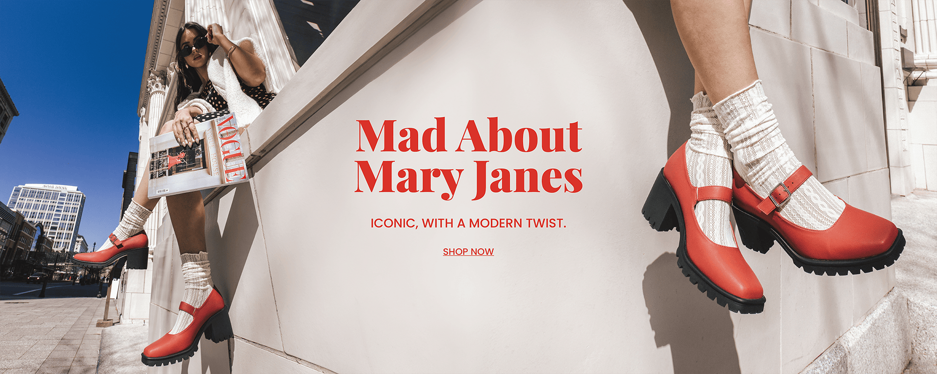 "Mad about Mary Janes" header text in red with "Iconic, with a modern twist." sub text. A model in a polka dot dress holding a fashion magazine with her red  Mary Jane shoes in focus. "Shop Now" call to action.