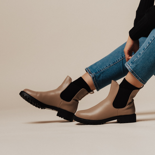 Close-up of tan Chelsea booties with block heels, paired with blue jeans.