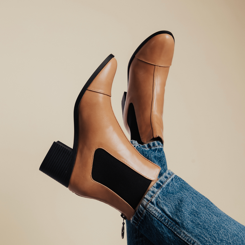 Close-up of tan Chelsea booties with block heels, paired with blue jeans.