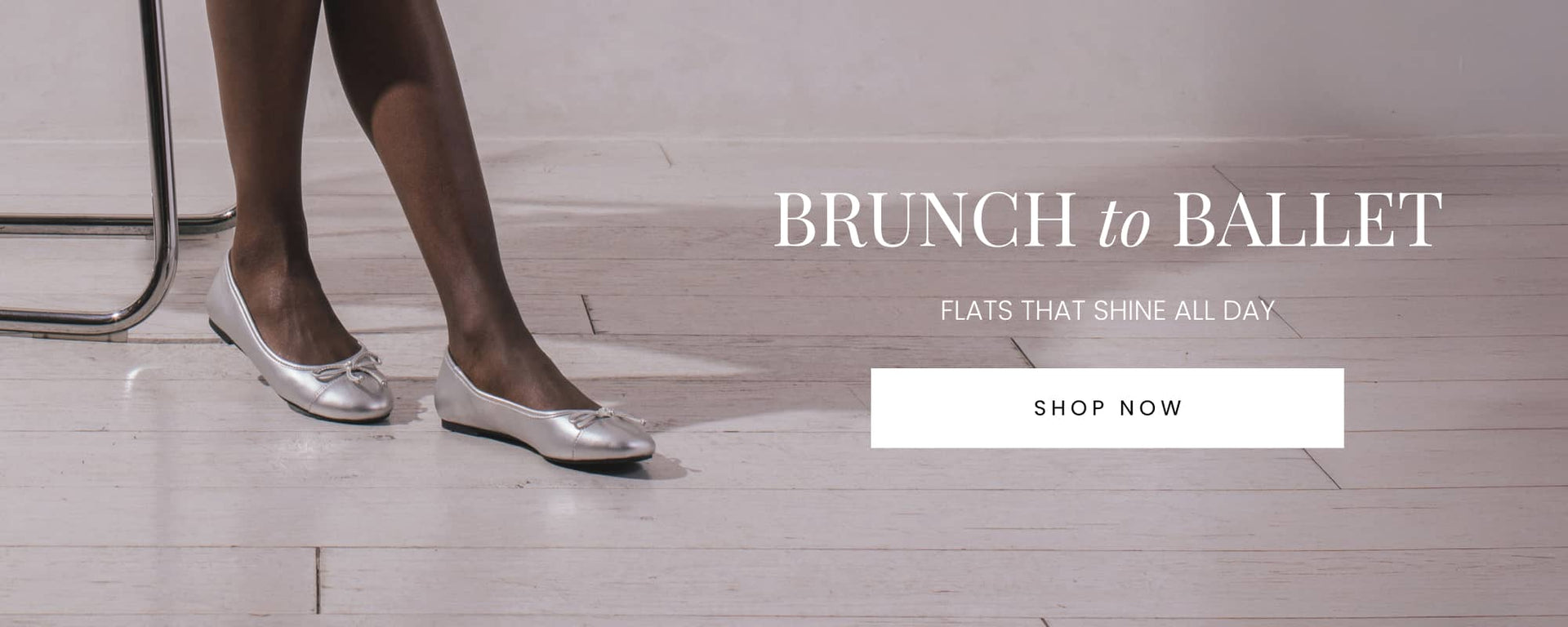 "Silver ballet flats worn by a person sitting on a chair with white wooden floors in the background. Text reads 'Brunch to Ballet – Flats That Shine All Day' with a 'Shop Now' button below."