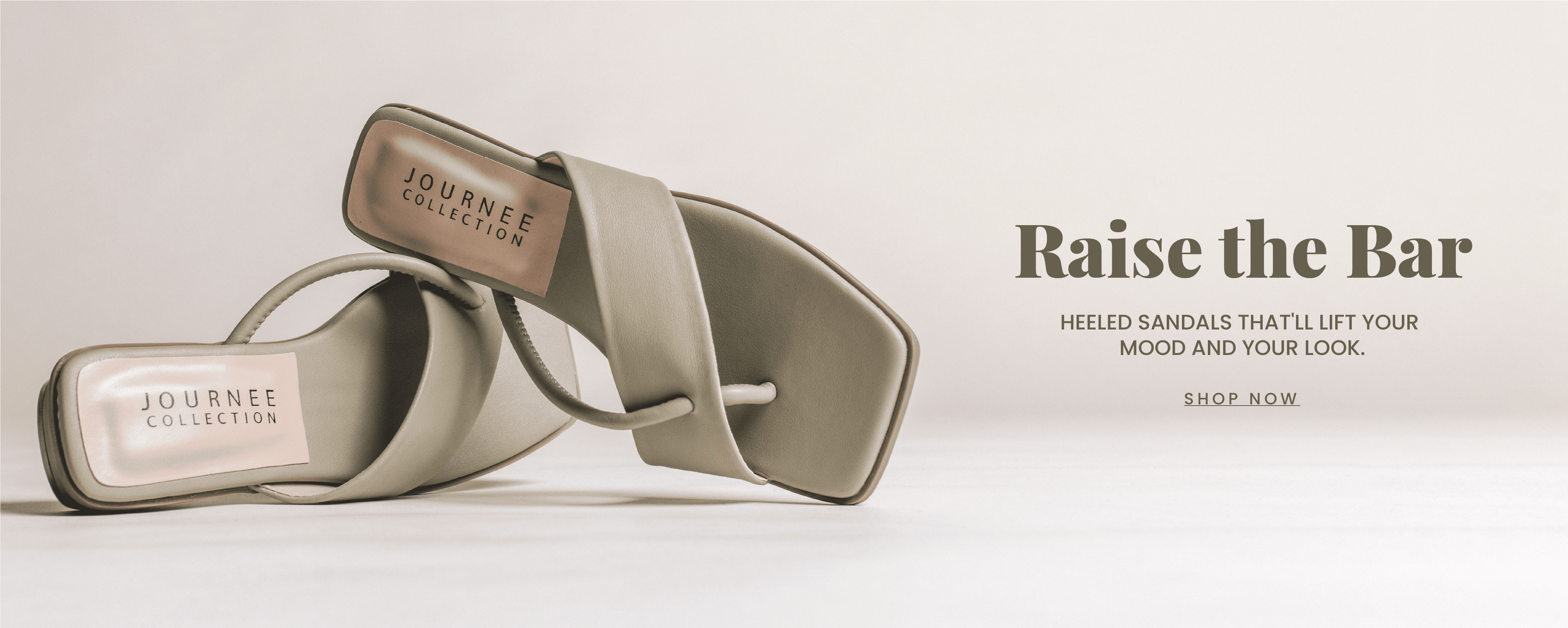 "Raise the Bar" header in olive green with "heeled sandals that will lift your mood and look" sub header. Olive green heeled sandals with asymmetrical straps are in focus. "Shop Now" call to action. 
