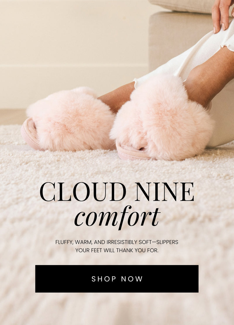 Close-up of a person wearing soft, fluffy pink slippers while seated on a cozy cream-colored carpet. The text overlay reads 'Cloud Nine Comfort' in bold and italicized fonts, with the description below: 'Fluffy, warm, and irresistibly soft—slippers your feet will thank you for.'