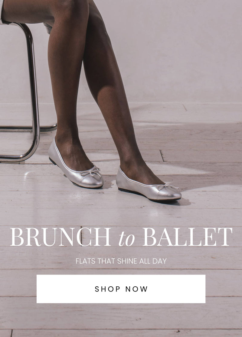 "Silver ballet flats worn by a person sitting on a chair with white wooden floors in the background. Text reads 'Brunch to Ballet – Flats That Shine All Day' with a 'Shop Now' button below."